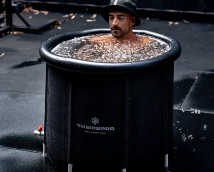 A man with a hat sitting in an ice bath