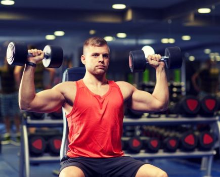 Man in a gym performing seated dumbbell press