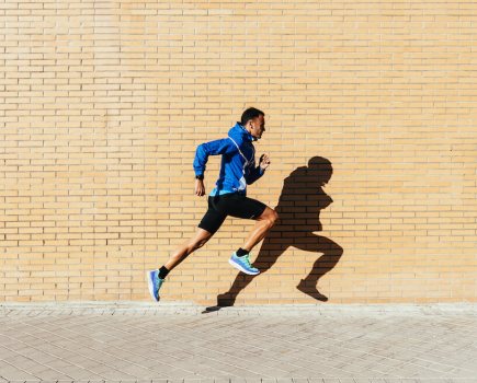 man running in front of brick wall