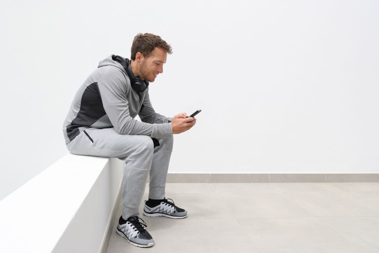 Man sitting, checking his phone, wearing sweatpants