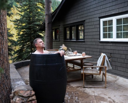 Man in an ice bath outside a cabin