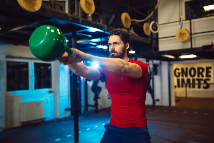 Man in a gym performing kettlebell swings