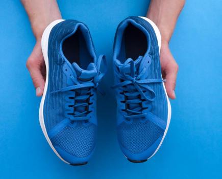 man holding pair of blue gym shoes