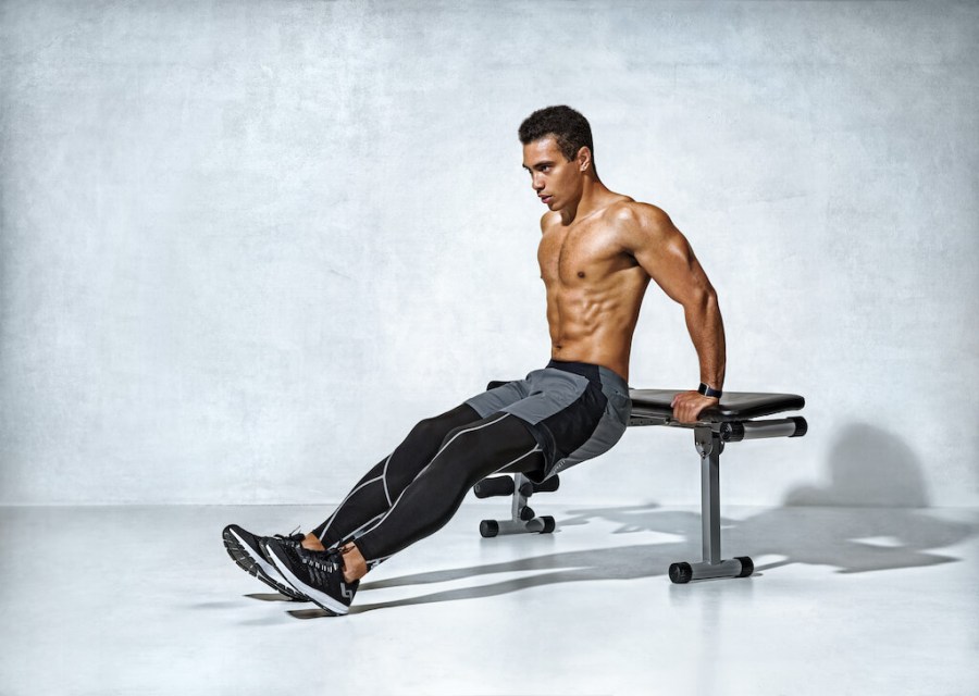 Topless man performing bench dip triceps exercise