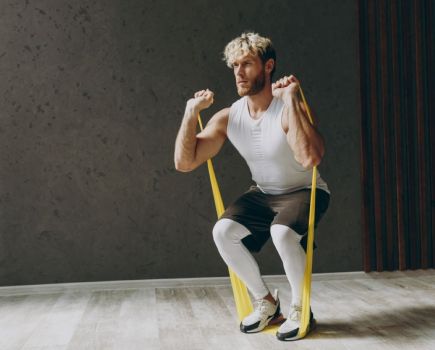 man using resistance band in full body workout, performing banded front squat
