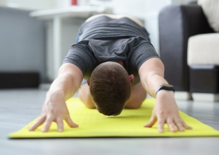 man performing back stretches at home