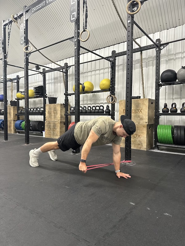 man performing band plank pull through exercise