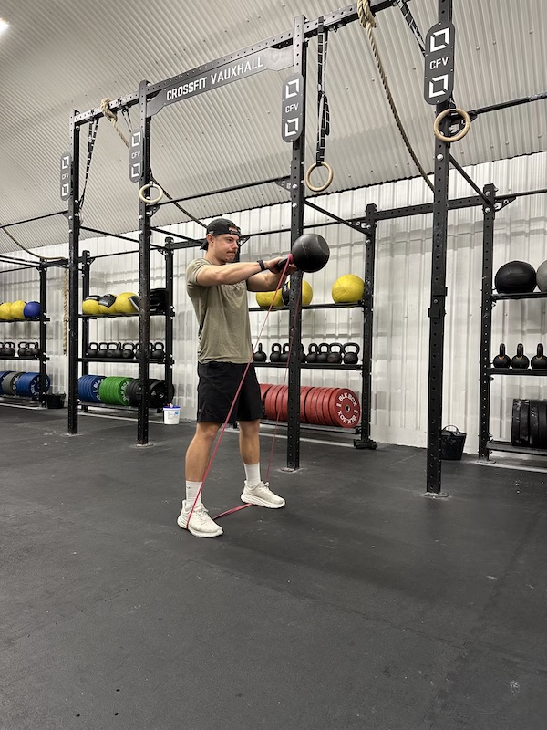 man performing band kettlebell swing exercise