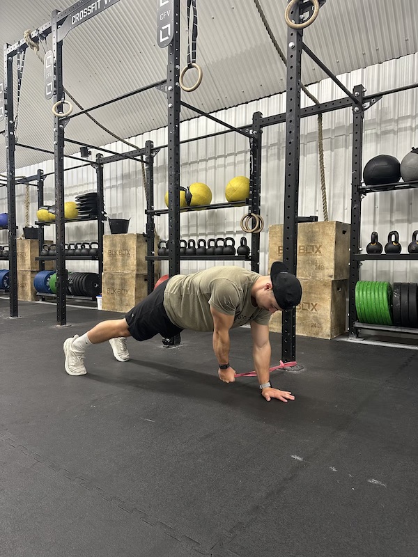 man performing band plank pull through exercise