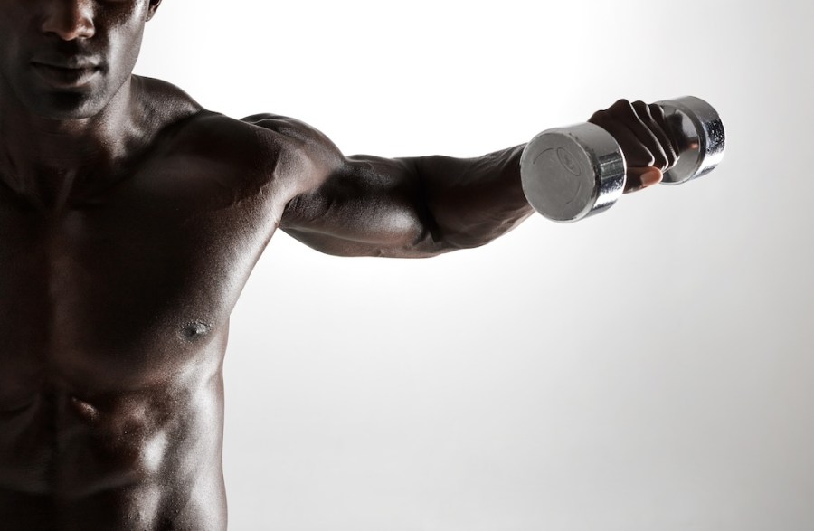 topless man performing dumbbell lateral raise as part of dumbbell shoulder workout