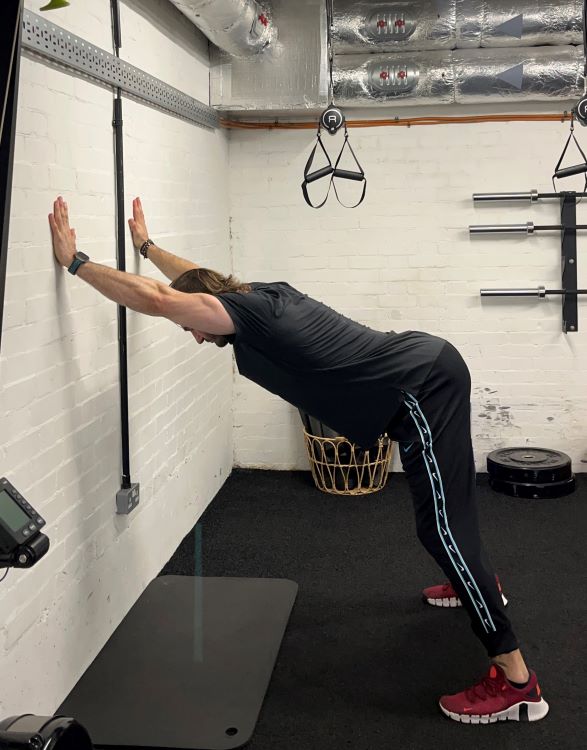 Man performing standing wall press - best back stretches