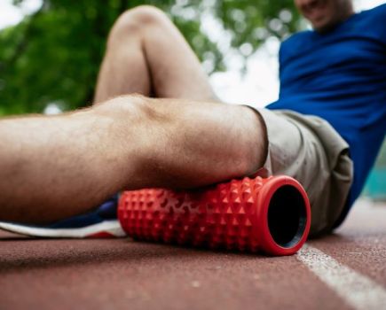 Close-up of a man massaging his quads with a foam roller