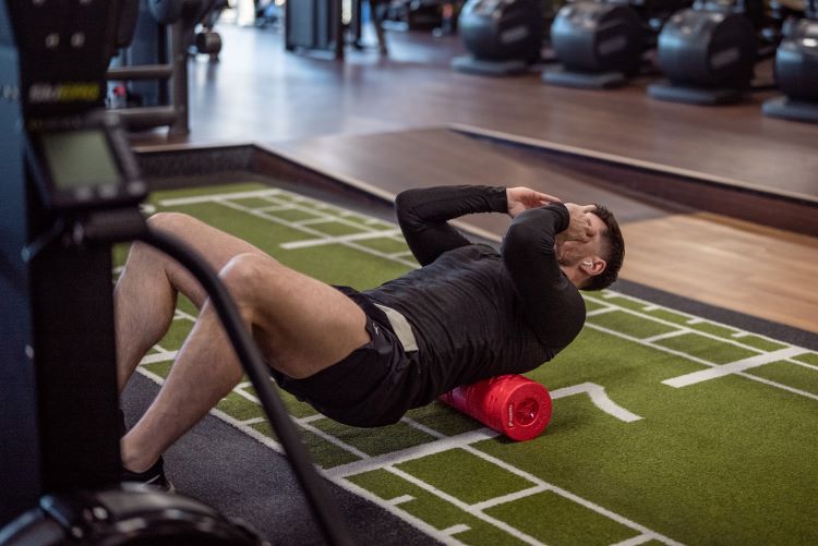 Man in a gym using a foam roller on his back