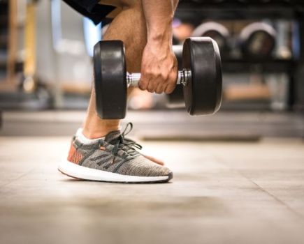 Close-up of a man's feet as he picks up dumbbells