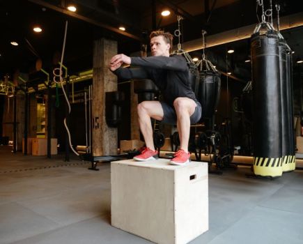 Man in gym performing box jumps