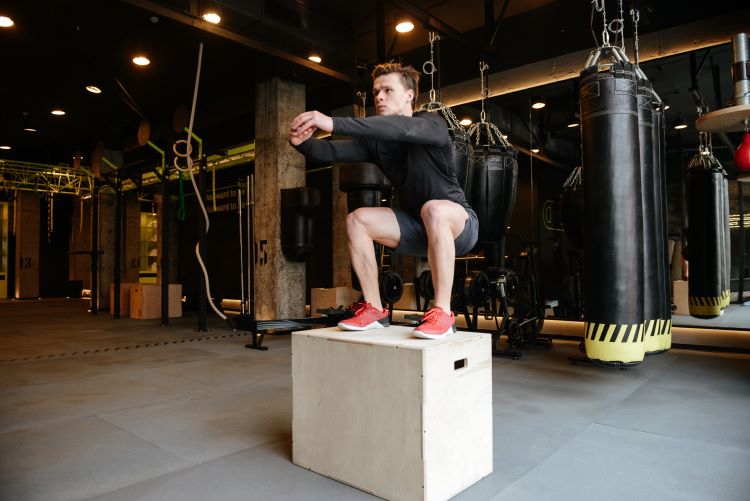 Man in gym performing box jumps