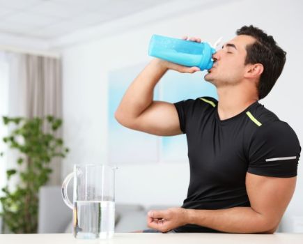 Man drinking pre-workout drink at home