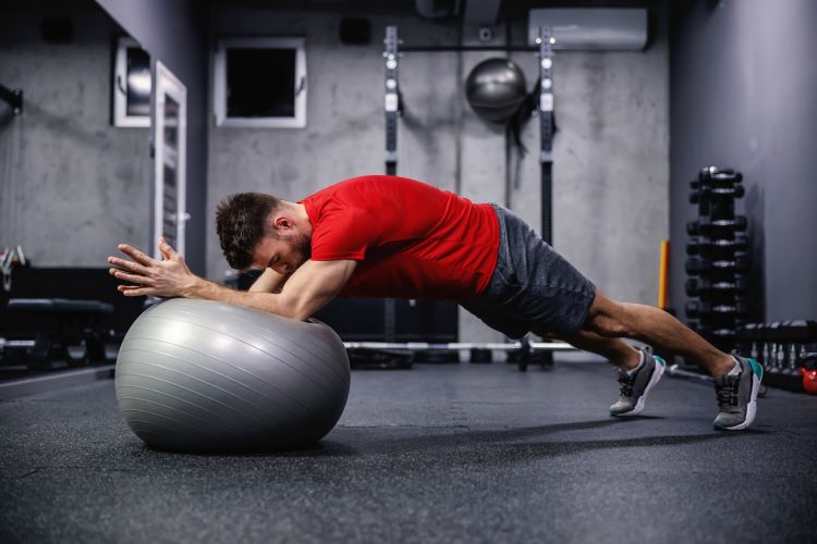 Man in a gym performing gym ball plank