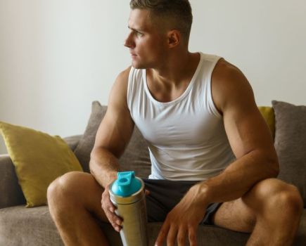 A man at home drinking a pre-workout shake
