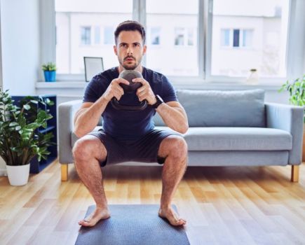 A man at home performing a kettlebell goblet squat