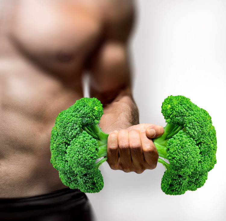Close-up of a man holding broccoli like a dumbbell