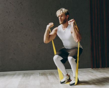 Man performing squats with a resistance band