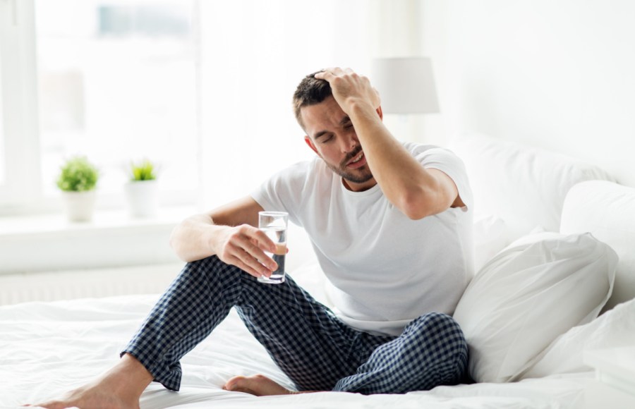 man with hangover in morning drinking electrolyte drinks