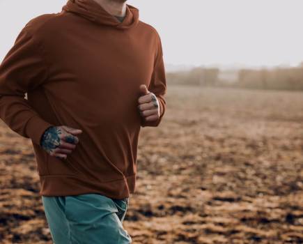 man jogging through countryside in hooded sweatshirt