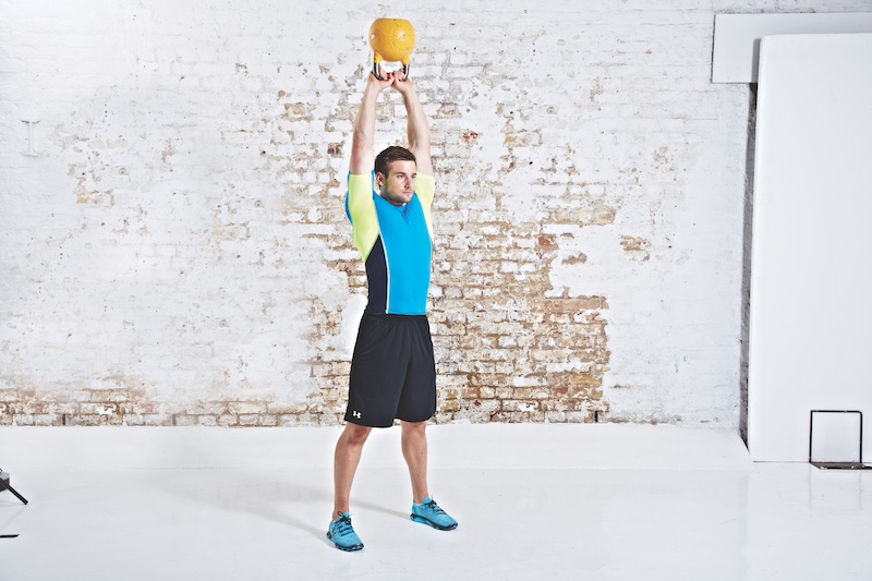 Man in blue top and black shorts performing kettlebell American swing