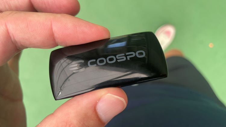 Close up of a man's hand holding a Coospo heart rate monitor