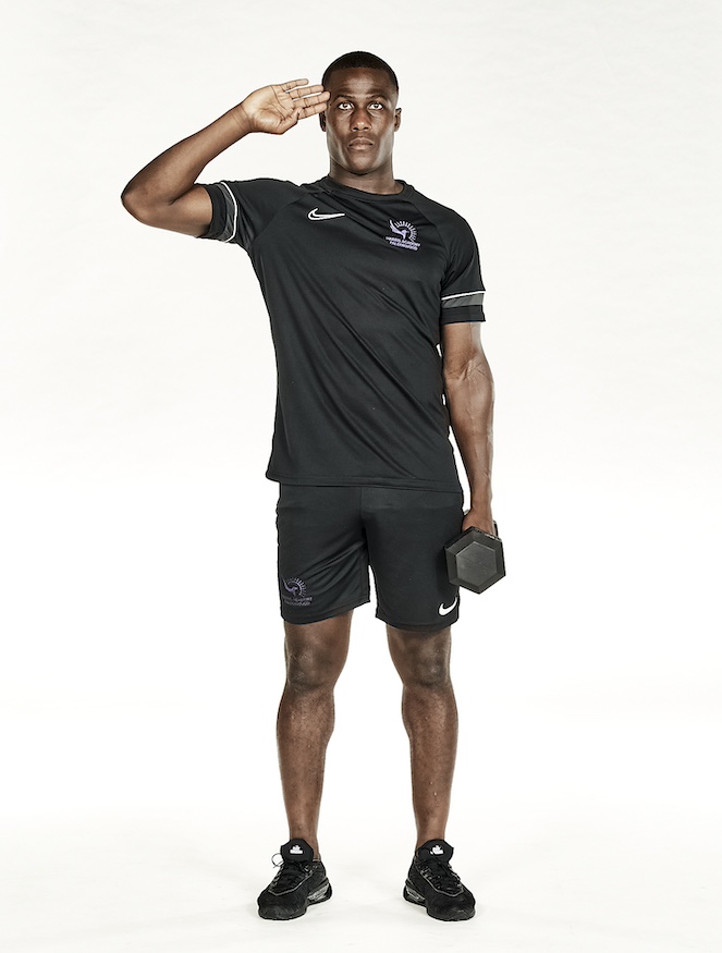 Man in black shorts and black training top performing dumbbell side crunch