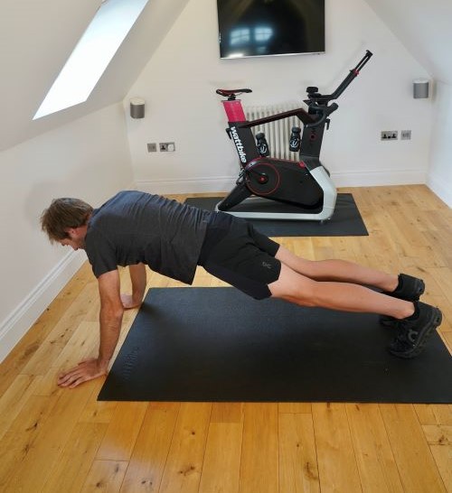 Man in home gym performing yoga poses, including the best strength exercises for cyclists