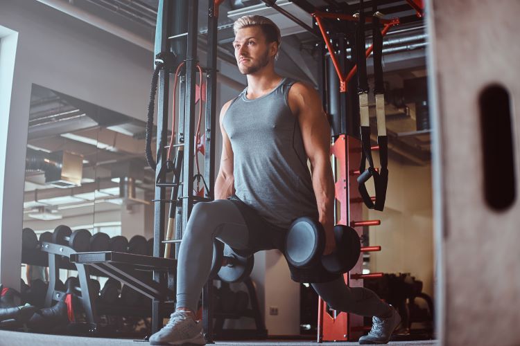 Man in gym performing dumbbell lunge