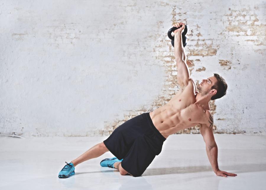 topless man performing Kettlebell Turkish get-up exercise