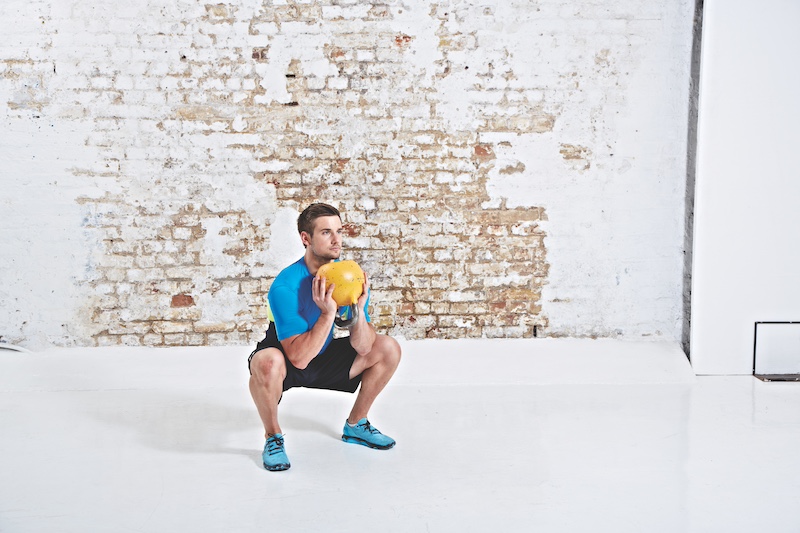 Man in blue top and black shorts performing kettlebell goblet squat