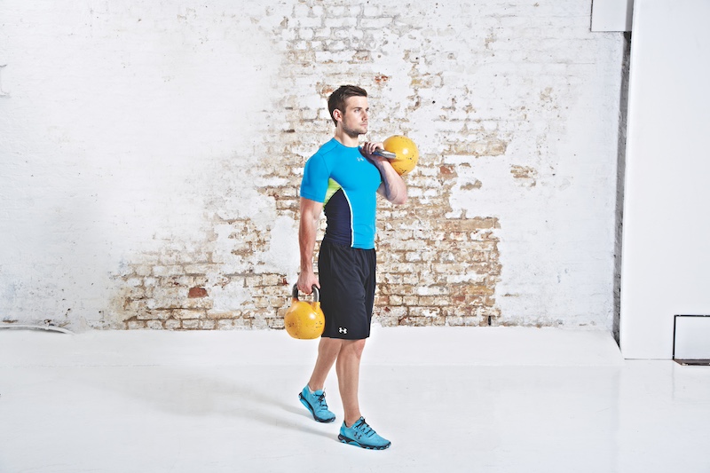 Man in blue top and black shorts performing kettlebell offset carry
