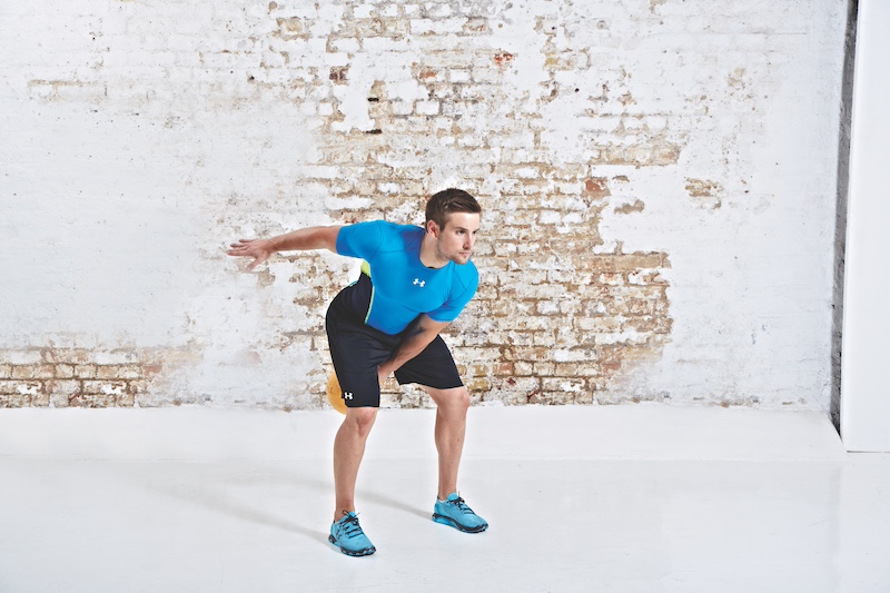 Man in blue top and black shorts performing kettlebell single-arm swing