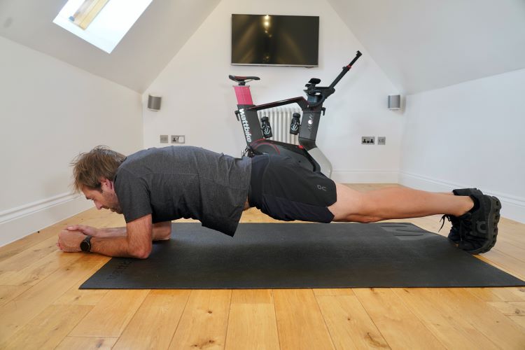 Man in home gym performing plank variations, One of the best strength exercises for cyclists