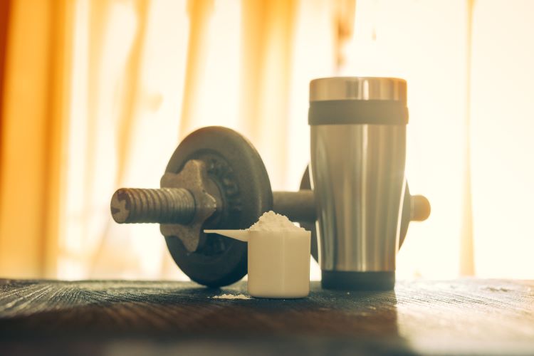 A serving of pre-workout powder, a shaker and dumbbell