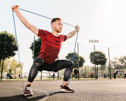 Man outside performing resistance band workout