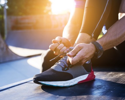 close up of man tying laces of running shoe