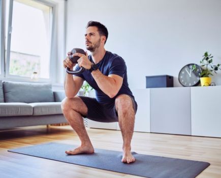 Man at home performing goblet squats