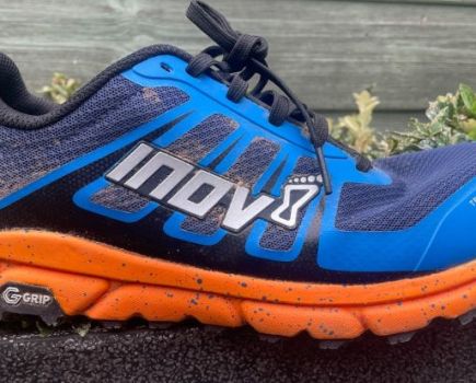 A used Inov8 trail running shoe on a wall