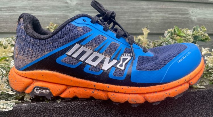 A used Inov8 trail running shoe on a wall