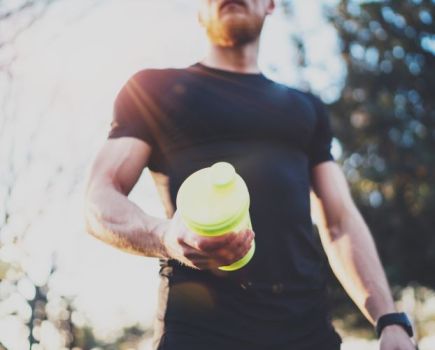 A man holding a bottle of pre-workout
