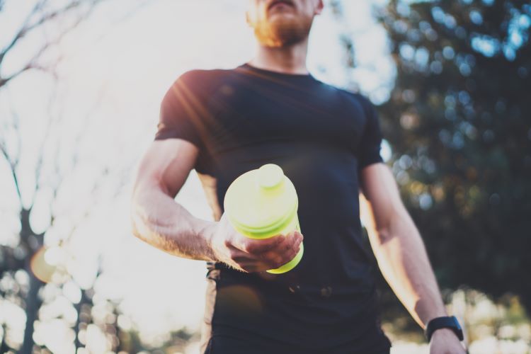 A man holding a bottle of pre-workout
