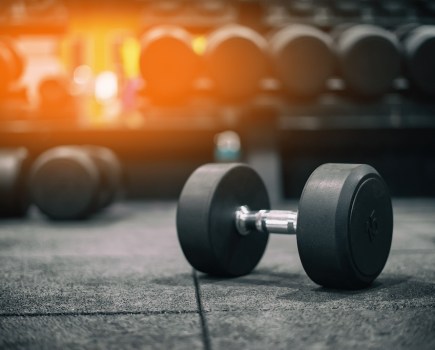 dumbbell on gym floor with other dumbbells racked in the background