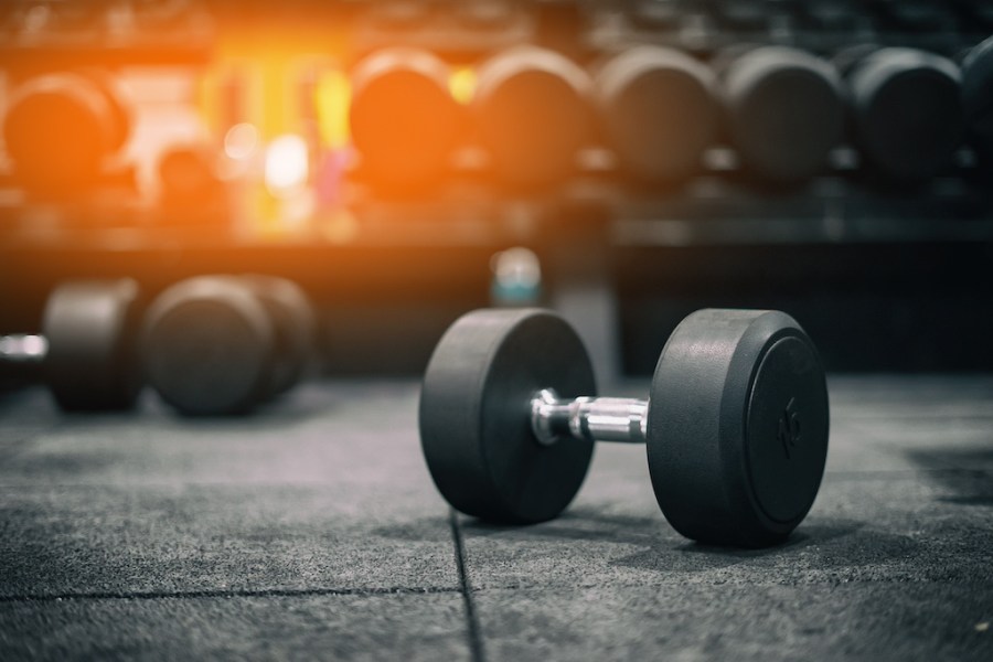 dumbbell on gym floor with other dumbbells racked in the background