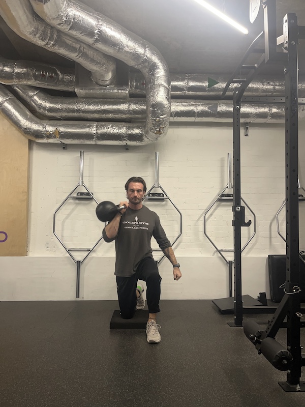 man performing half-kneeling kettlebell press in the gym