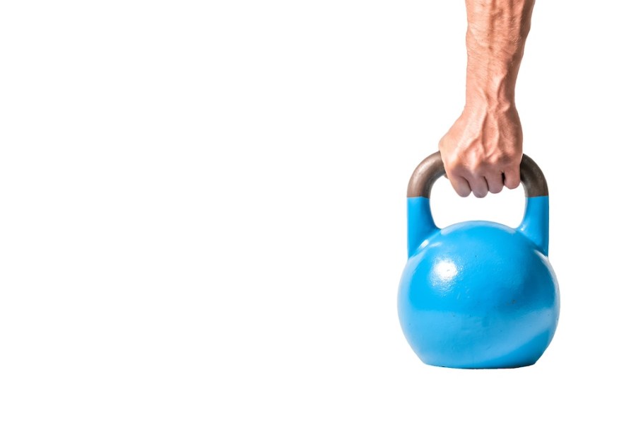 Strong muscular man hand with muscles holding blue heavy kettlebell partially isolated on white background